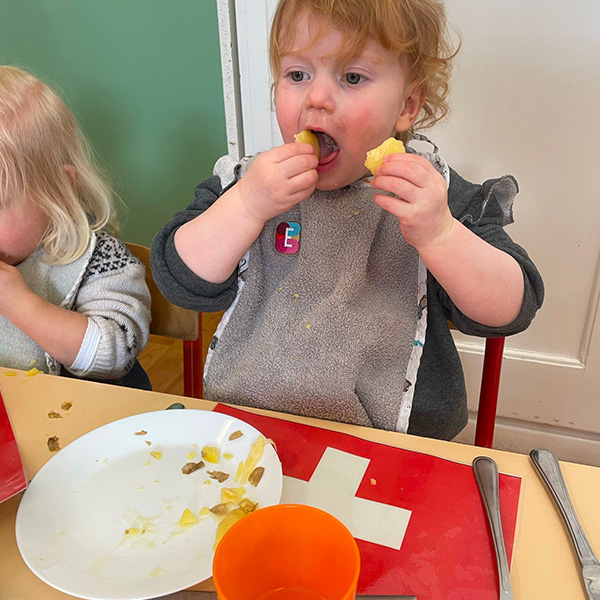 Une enfant mange avec enthousiasme des morceaux de pommes de terre et fromage fondu.