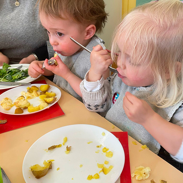 Deux enfants dégustent leur raclette avec appétit, concentrés sur leur repas.