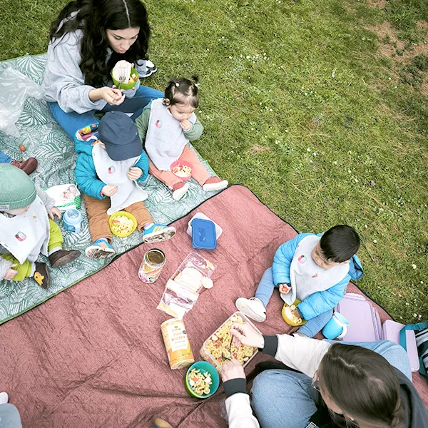 Moment de pique-nique sur l’herbe pour les enfants de la garderie à Lausanne, pendant une sortie printanière.