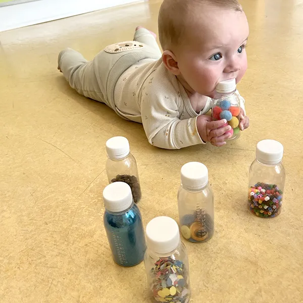 Gros plan sur une quille sensorielle remplie de perles et de paillettes, utilisée dans la nurserie à Lausanne.