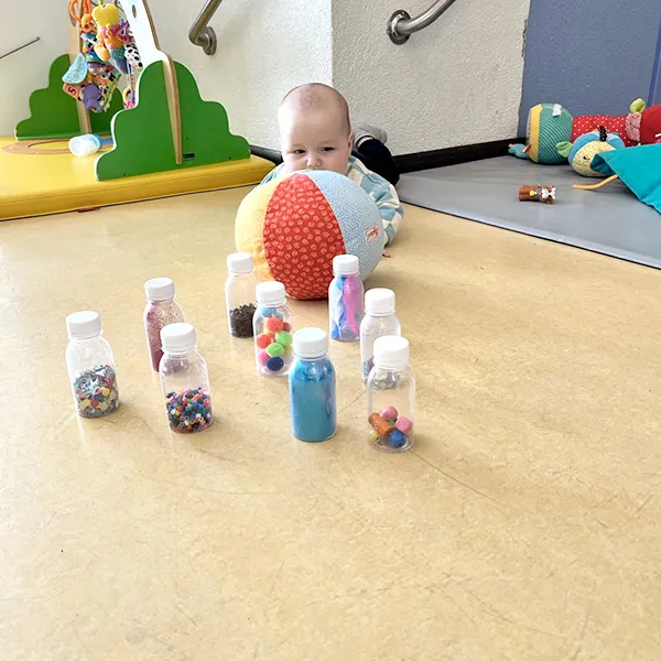 Vue d’ensemble d’un atelier sensoriel avec plusieurs quilles alignées sur un tapis de jeu à Lausanne.