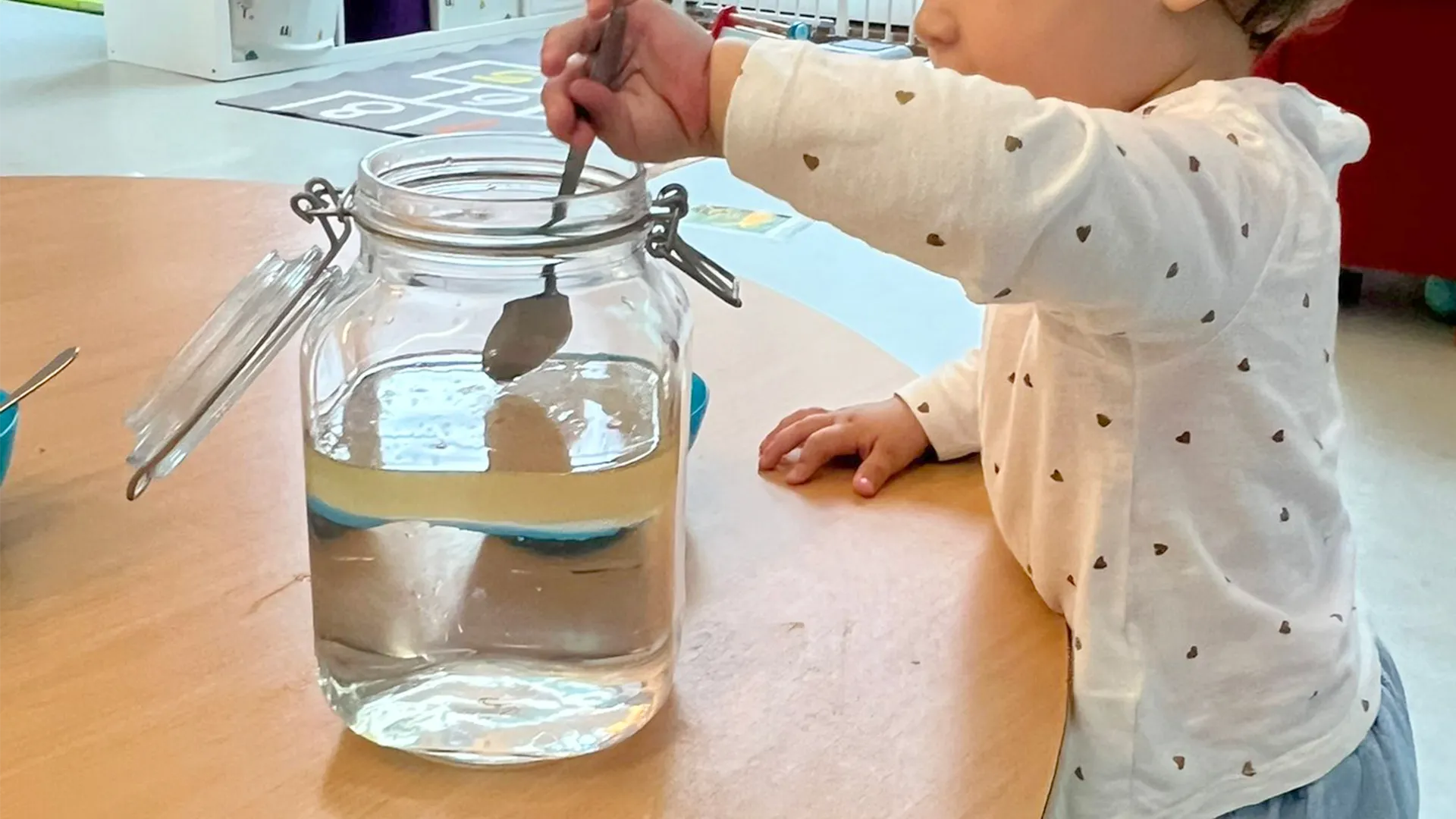 Gouttelettes colorées descendant dans l’huile, observées par des enfants émerveillés à la garderie.
