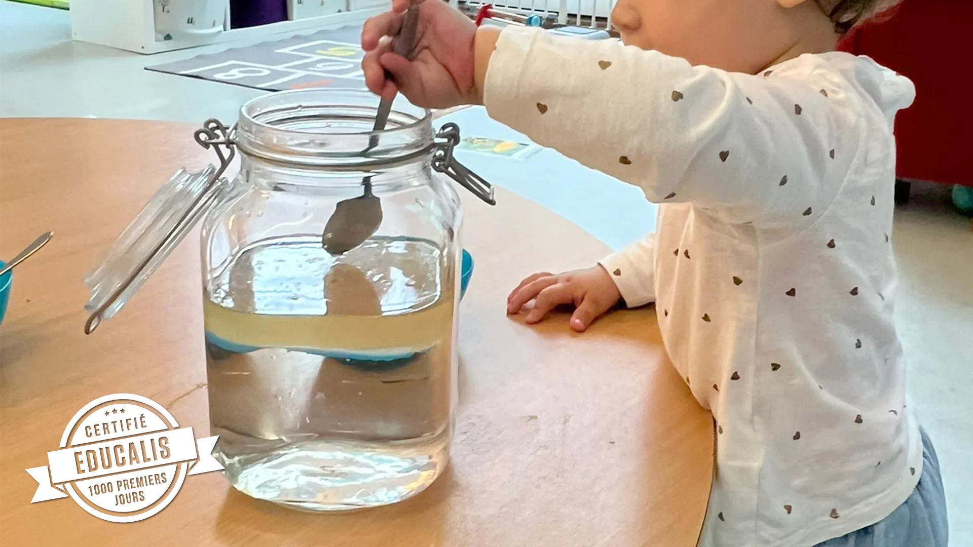 Gouttelettes colorées descendant dans l’huile, observées par des enfants émerveillés à la garderie.
