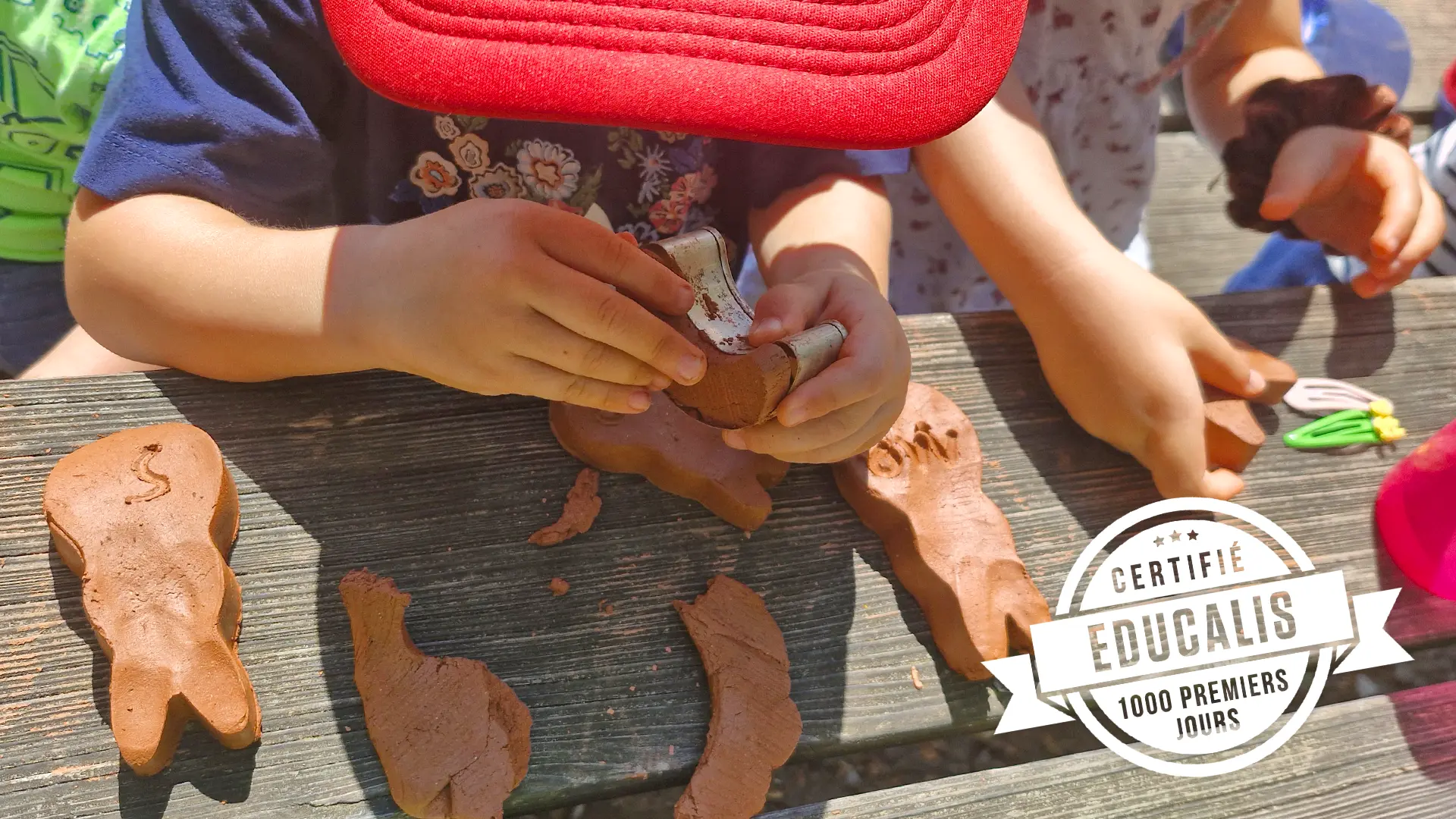 Enfant modelant un petit bol en terre lors de l’atelier poterie au parc à Lausanne.