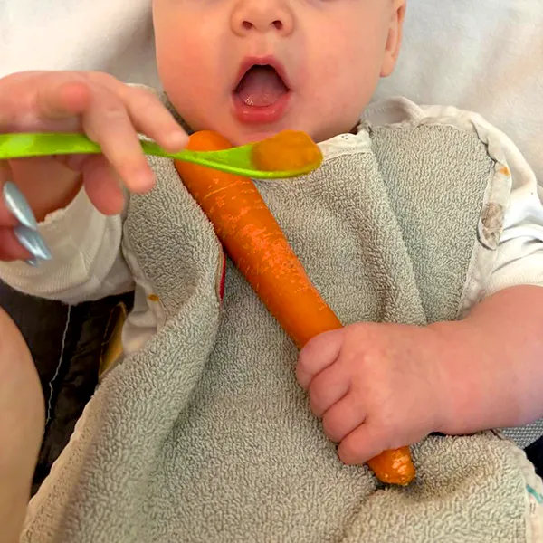 Bébé explorant une carotte crue à la crèche Les Petits Acrobates à Lausanne.
