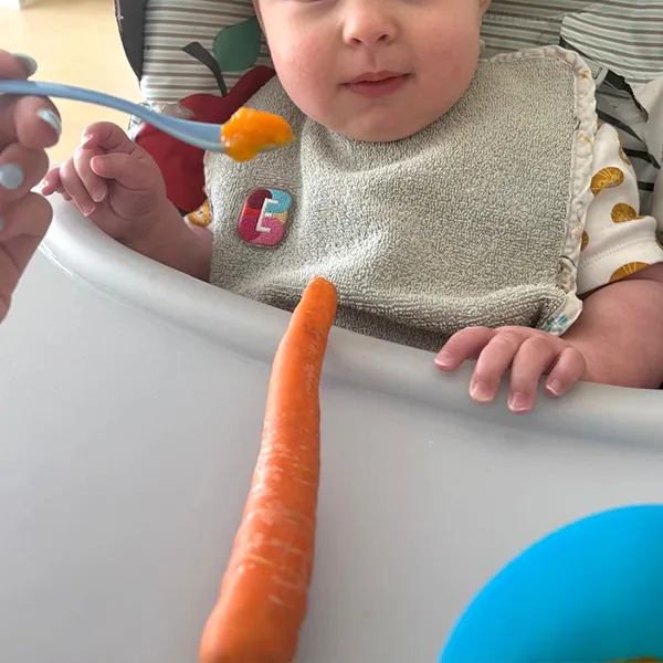 Bébé explorant une carotte crue à la crèche Les Petits Acrobates à Lausanne.