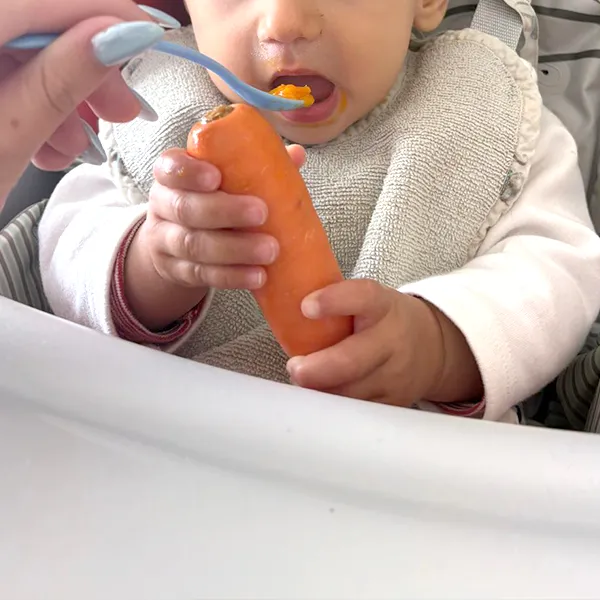 Bébé explorant une carotte crue à la crèche Les Petits Acrobates à Lausanne.